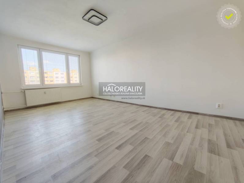 Szoba nagy ablakokkal és fa dekorációjú padlóval egy kétszobás lakásban.