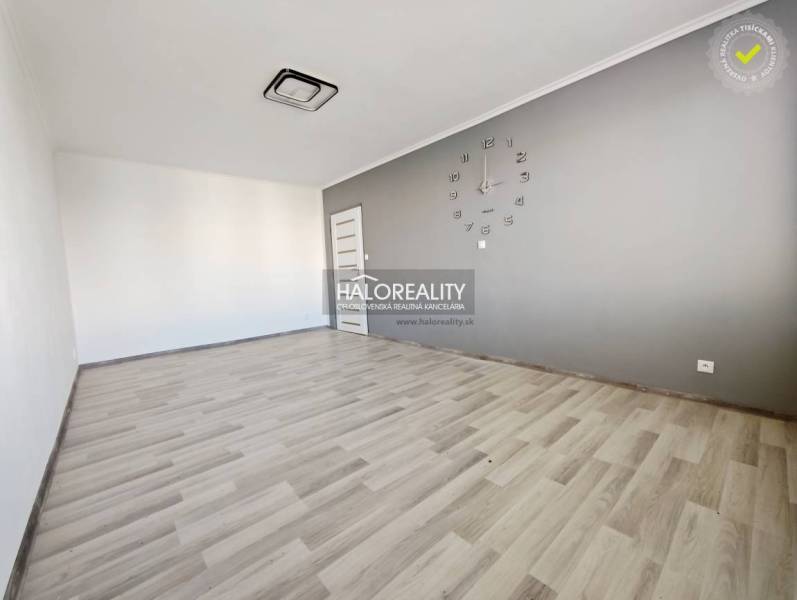 Szoba órával és fa dekorációjú padlóval egy kétszobás lakásban.