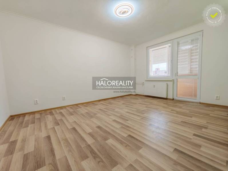 Tágas szoba egy kétszobás lakásban, fa dekorációjú padlóval.