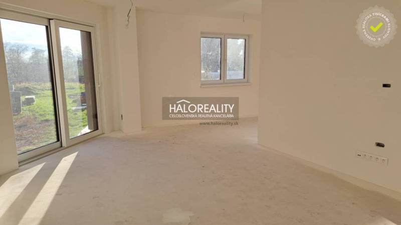 Családi ház belső tere nagy ablakkal, fehér falakkal és teraszajtókkal.