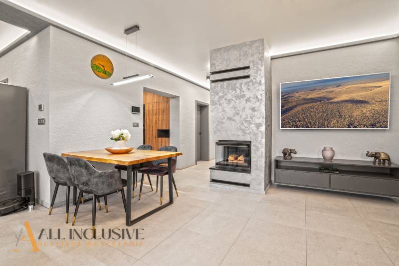 Nappali egy családi házban kandallóval, négy személyes asztallal és dekorációkkal.