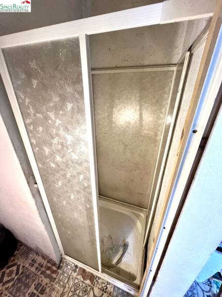 Zuhanykabin családi ház belső terében burkolattal és dekoratív padlóval.