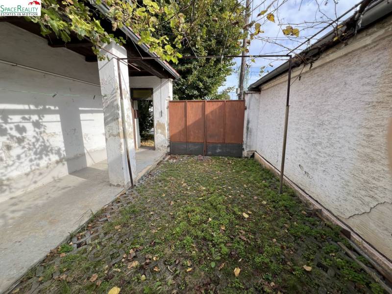 Egy családi ház udvara Jablonecben kőburkolattal és zöld növényzettel.