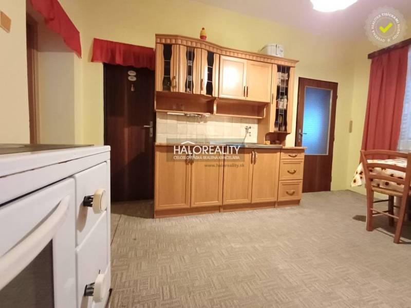 Konyha egy családi házban, fa szekrényekkel és hagyományos tűzhellyel.