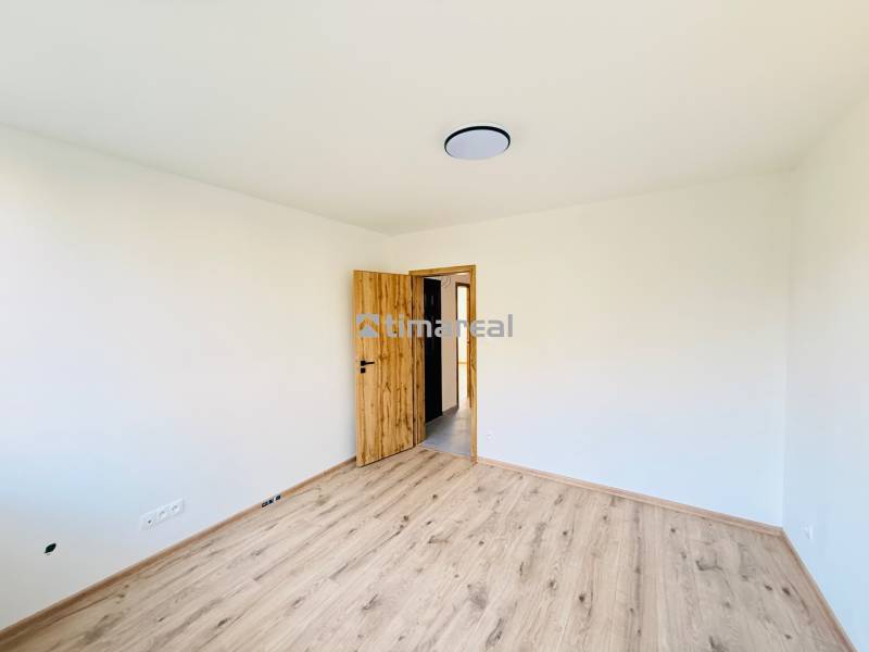 Szoba egy háromszobás lakásban fehér falakkal és fa dekorációjú padlóval.