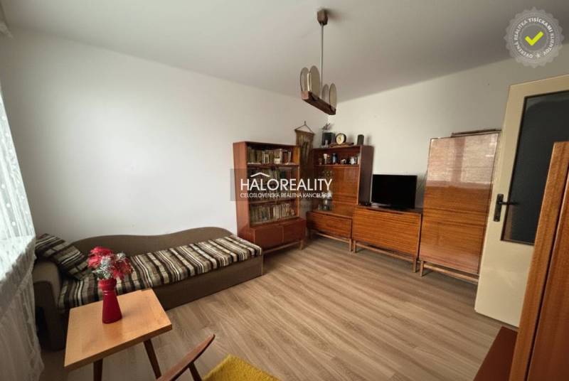 Nappali egy háromszobás lakásban fa mintázatú padlóval, fa bútorokkal, kanapéval.