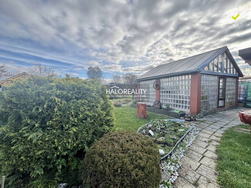 Kertek Iglón üvegházzal, rendezett gyepfelülettel és virágágyással.