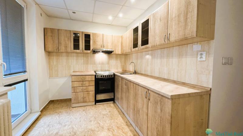 Konyha egy háromszobás lakásban fa dekorációjú szekrényekkel és csempével.