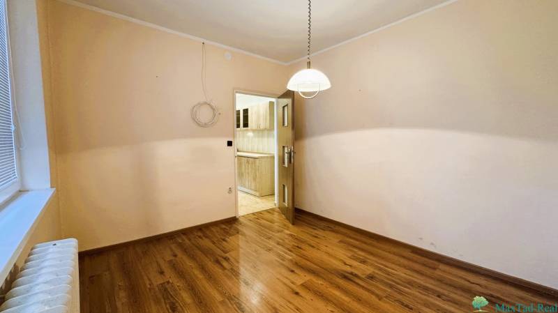 Szoba egy háromszobás lakásban fa dekor padlóval, kilátás a konyhába.