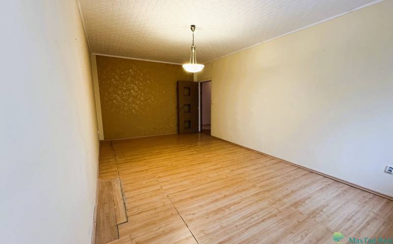 Nappali szoba fa dekor padlóval, csillárral és mintás fal egy háromszobás lakásban.