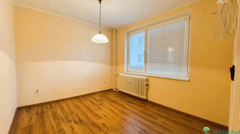 Szoba egy háromszobás lakásban fa dekor padlóval és nagy ablakkal.