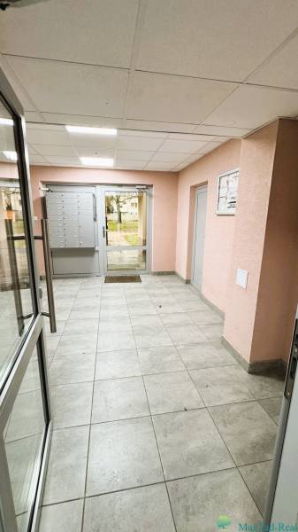 Lakóház előcsarnoka postaládákkal és üvegajtókkal.