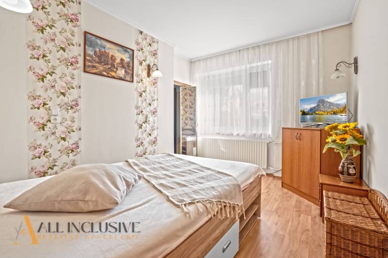 Hálószoba családi házban, ággyal, virágmintás tapétával és fa dekorációjú padlóval.