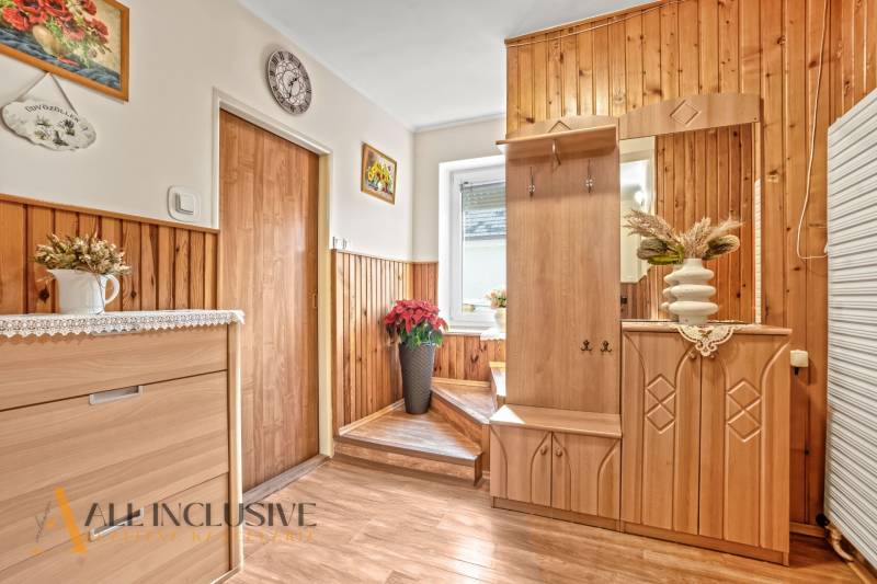 Egy családi ház folyosója fa burkolattal, dekorációkkal és fa mintázatú padlóval.