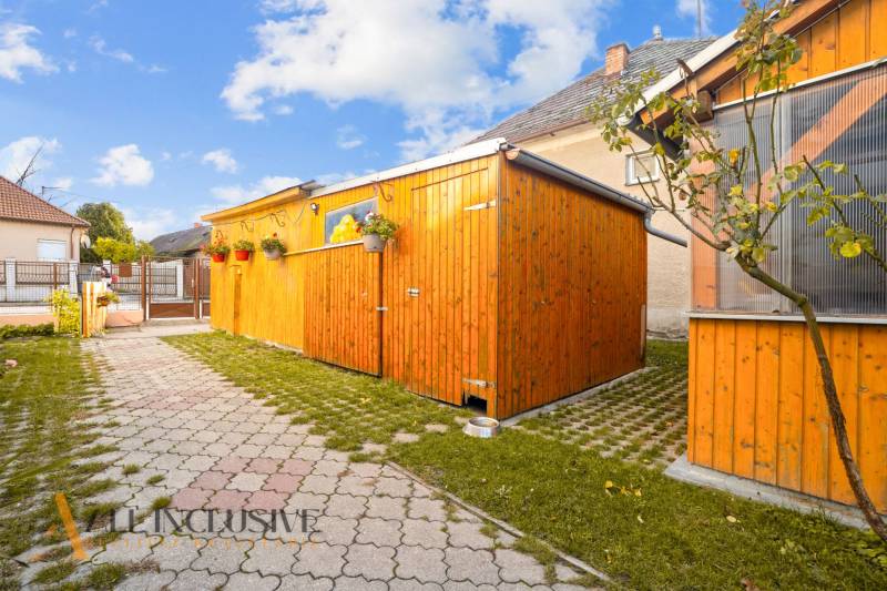 Egy családi ház udvara Dunaszerdahelyen, fa előtetővel és kövezett járdával.