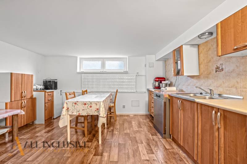 Konyha egy családi házban fa dekor padlóval, természetes szekrényekkel, világos asztallal.