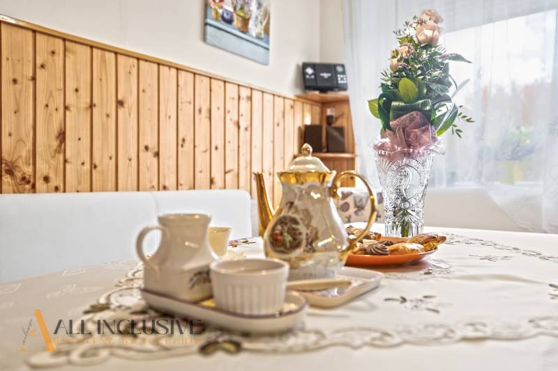 Teáskészlet az asztalon, virágok a vázában, hidegtál a családi házban.