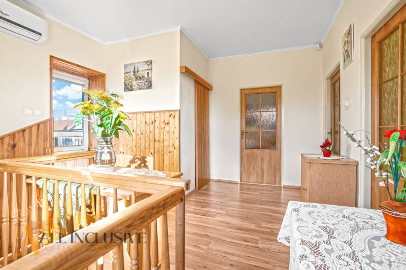 Családi ház belső tere fa dekorációjú padlóval, korláttal és dekorációkkal.