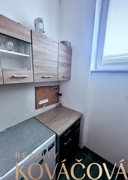 Irodák konyhával, fa dekorációjú szekrényekkel és kis ablakkal a megvilágításhoz.