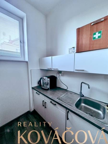 Irodai konyhasarok szekrényekkel, mosogatóval és kávéfőzővel.