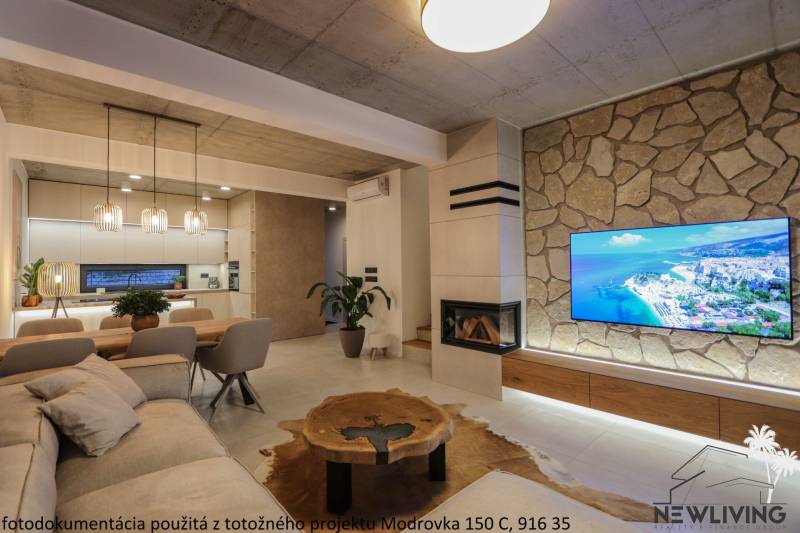 Nappali családi házban kandallóval, kőfalra szerelt TV-vel és fa mintázatú padlóval.