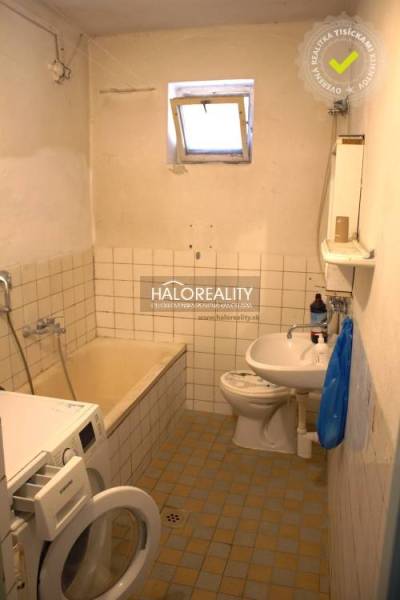 Fürdőszoba régebbi káddal, mosdóval és mosógéppel egy családi házban.