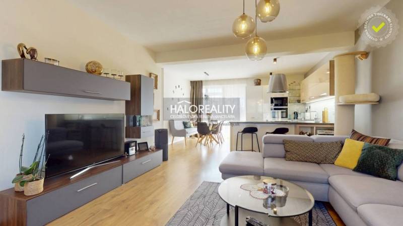 Nappali fa dekor padlóval, kényelmes kanapéval és tágas konyhával egy családi házban.