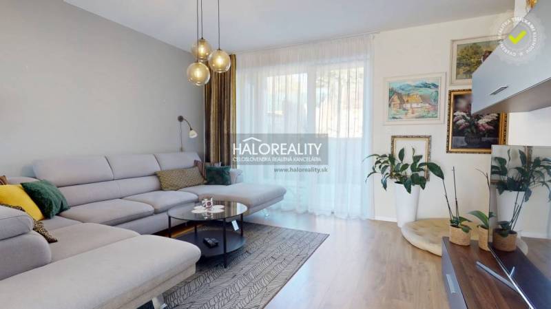 Nappali egy családi házban kényelmes kanapéval, fa dekorációjú padlóval és növényekkel.