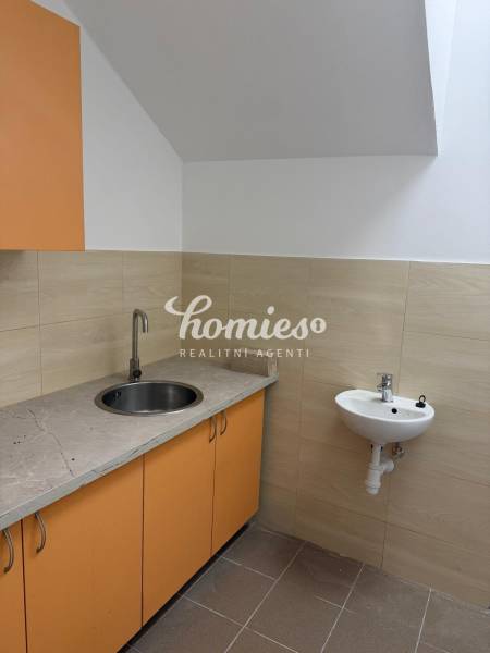 Konyhasarok üzlethelyiségben narancssárga szekrényekkel és mosogatóval.