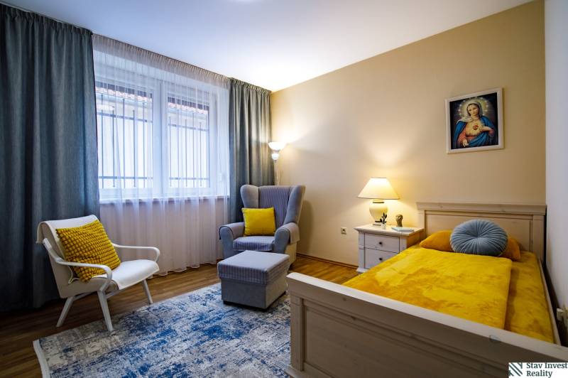 Szoba családi házban ággyal, székkel, asztallal és fa mintázatú padlóval.