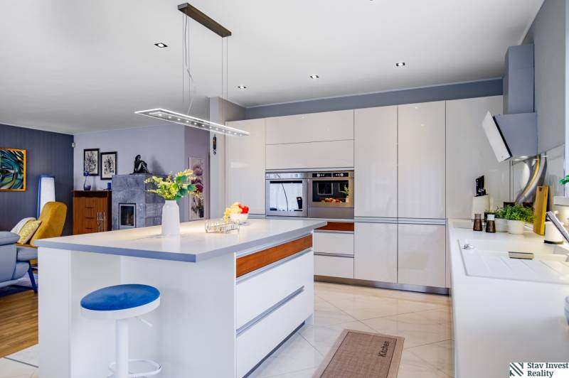 Családi ház konyhája szigettel, lámpával, beépített sütővel és kiegészítőkkel.