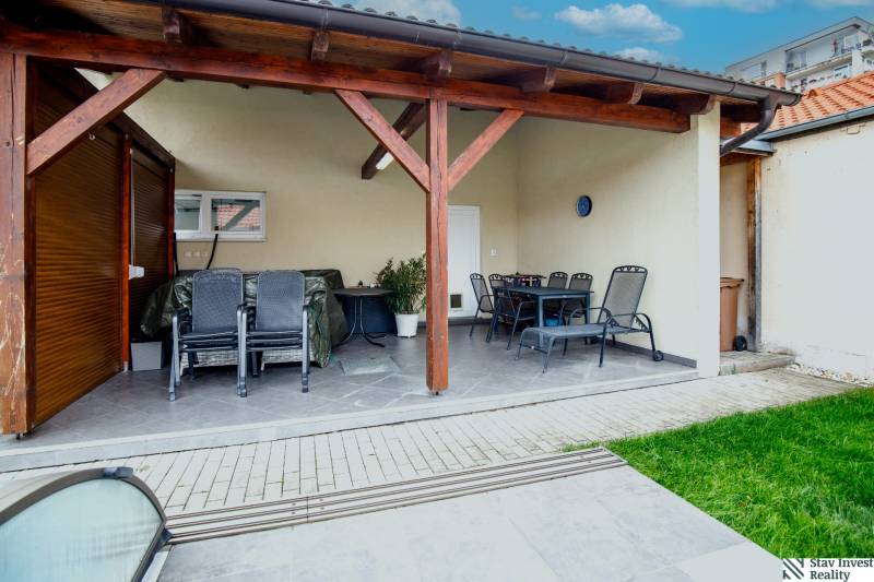 A Školská utcai családi ház terasza Szencen, kültéri ülőhellyel és tetővel.