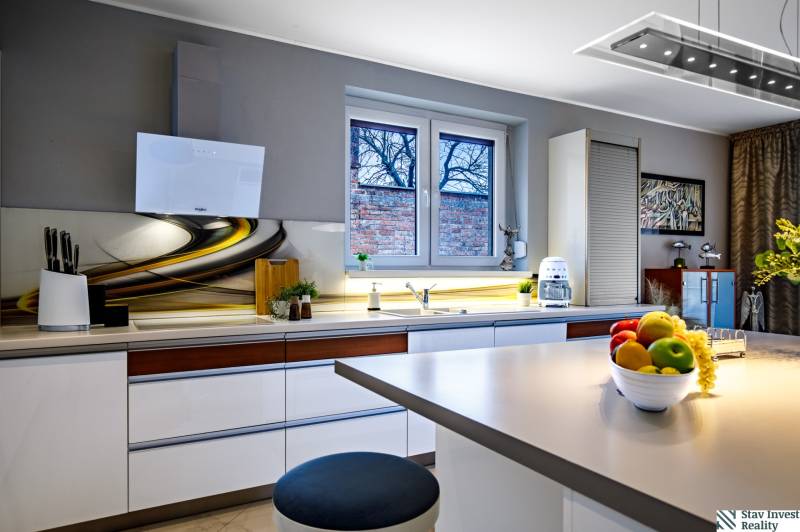 Konyha családi házban stílusos munkalappal, fehér szekrényekkel és dekorációkkal az ablakon.