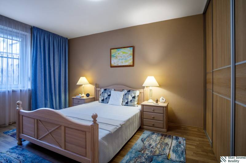 Hálószoba családi házban ággyal, éjjeliszekrényekkel és fa dekorációjú padlóval.