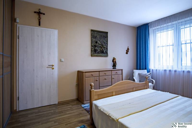 Hálószoba fa dekor padlóval egy családi házban, fa ágy és komód.