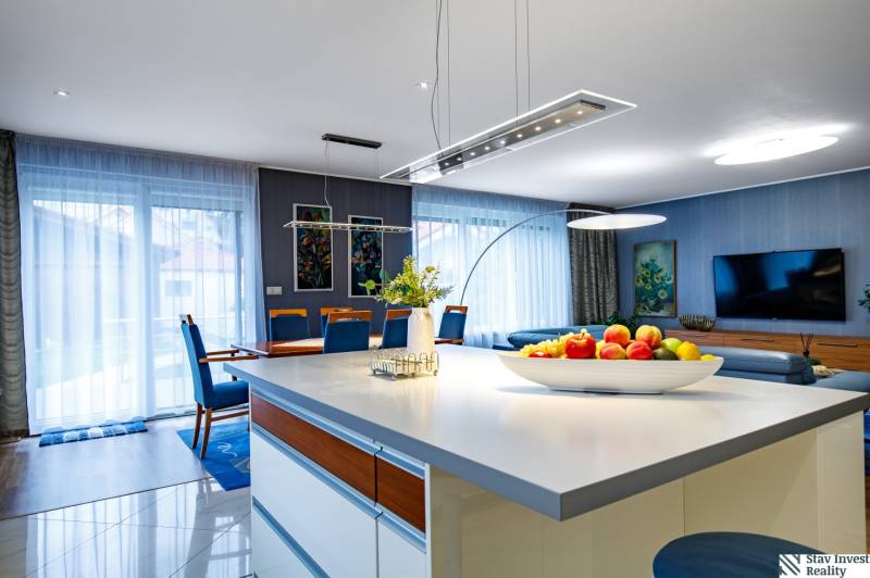 Nappali egy családi házban konyhaszigettel, kanapéval és étkezőasztallal.