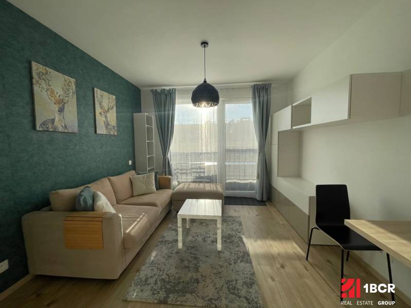 Nappali egy egyszobás lakásban kanapéval, szarvas dekorációval és fa mintázatú padlóval.