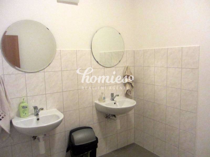 Fürdőszoba két mosdóval és kerek tükrökkel az irodában.