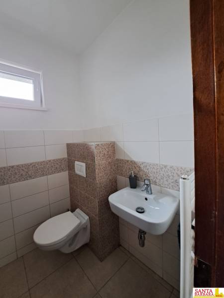 Négy szobás lakás WC-je fehér és mintás csempékkel.