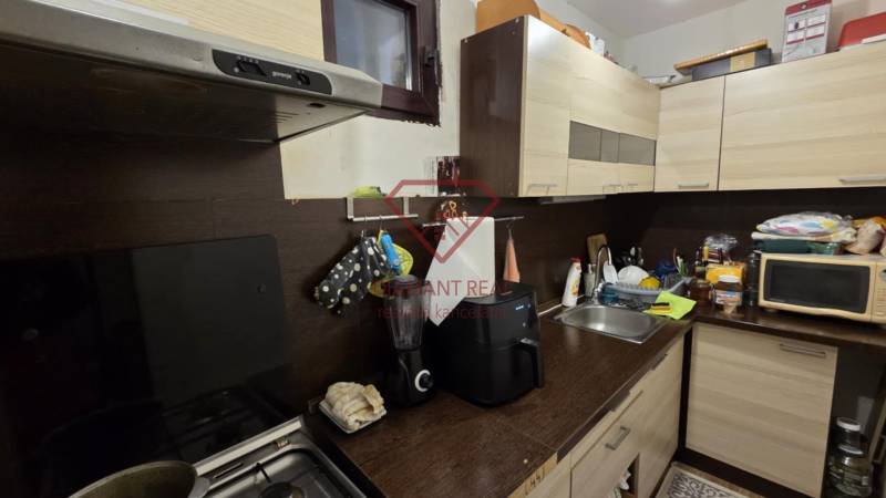 Családi ház konyhája konyhabútorral, mosogatóval és háztartási gépekkel.