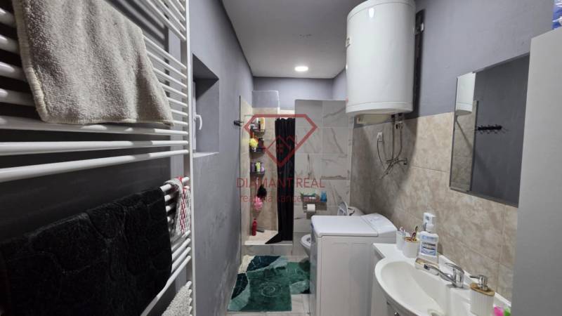 Fürdőszoba családi házban mosdóval, mosógéppel, bojlerrel és zuhanyzóval.