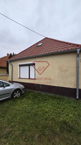 Családi ház a Nagy utcán Nagymácsédon, autóval a gyepen.