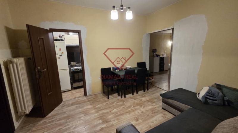 Nappali egy családi házban, fa mintázatú padlóval, asztallal és kanapéval.