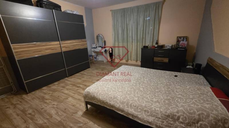 Hálószoba családi házban fa dekor padlóval, gardróbszekrénnyel és ággyal.