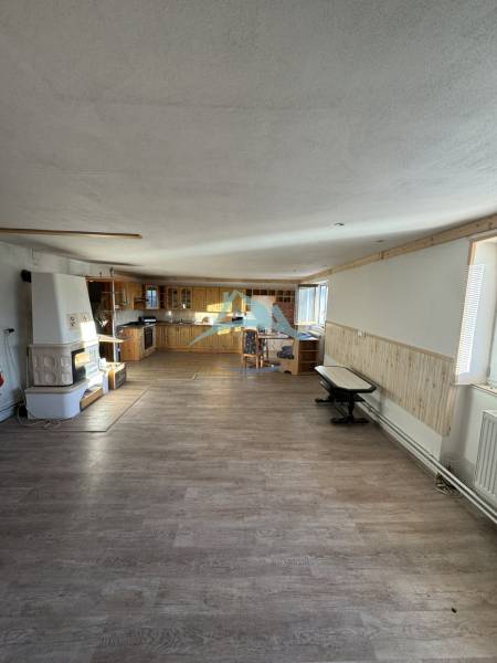 Családi ház belső tere konyhasarokkal, téglából épített kemencével és fa dekorációjú padlóval.