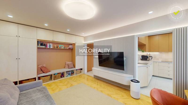 Nappali egy háromszobás lakásban, fa dekorációjú padlóval és beépített tárolóhellyel.