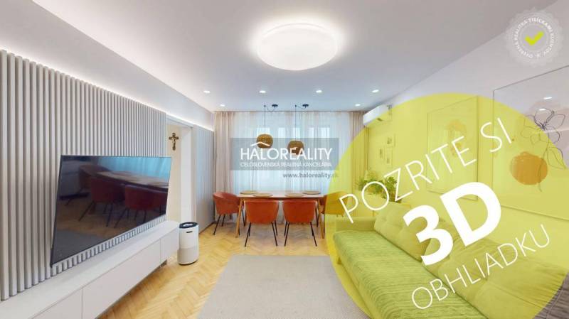 Nappali egy háromszobás lakásban, televízióval, kanapéval és fa padlódekorációval.