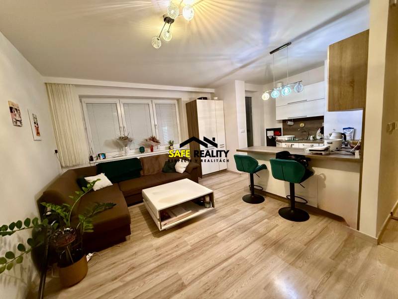 Nappali és konyha egy kétszobás lakásban, fa mintázatú padlóval.