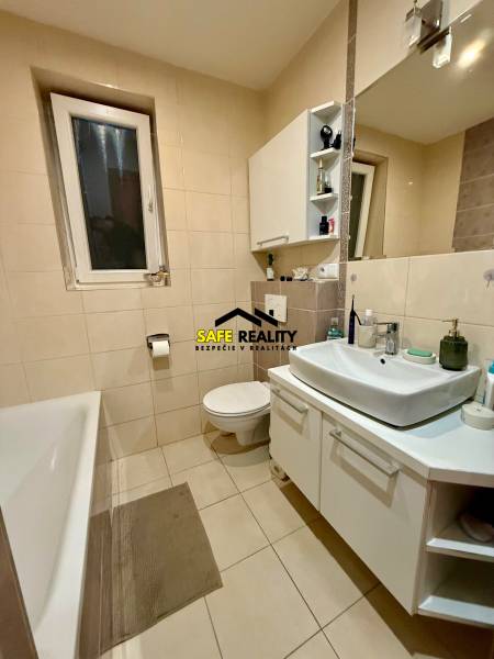 Fürdőszoba káddal és fehér mosdókagylóval egy kétszobás lakásban.