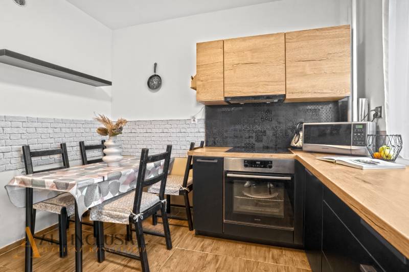 Konyha fa dekorációval, étkezőasztallal és háztartási gépekkel egy háromszobás lakásban.